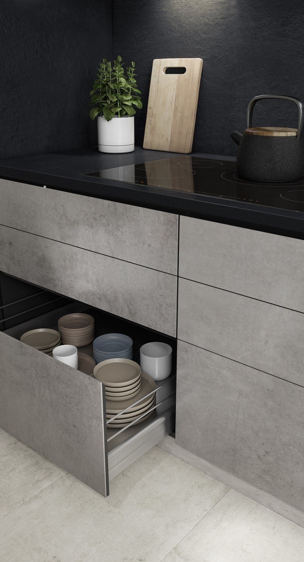 Modern grey kitchen cabinets with an open drawer showing neatly stacked plates and ceramic bowls.