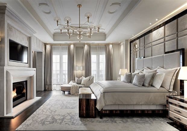 Luxurious neutral-toned bedroom featuring a large bed, fireplace, and a modern glass globe chandelier.