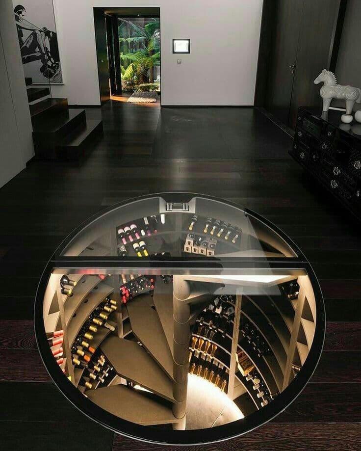 Circular glass floor opening reveals a spiral staircase leading to an underground wine cellar.